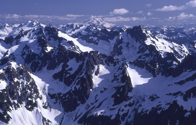 The Ptarmigan Traverse follows the lit up snowfield and glacier running through the middle of this image and we climbed most of the rocky summits in the middle / from summit of Sahale Mtn. near Cascade Pass / Washington. Photo by Fred Pflughoft.