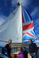 Running Downwind with the Spinnaker Up / Our Friends Betsy & Ian (Sister & Brother and Owners of the West Sound Marina) on either side of Sue who is manning the Helm. Photo by Fred Pflughoft.