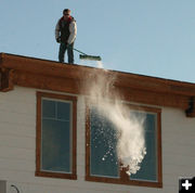 Brushing snow off the roof. Photo by Dawn Ballou, Pinedale Online.